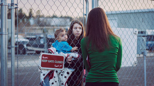 woman with child standing at shelter gate