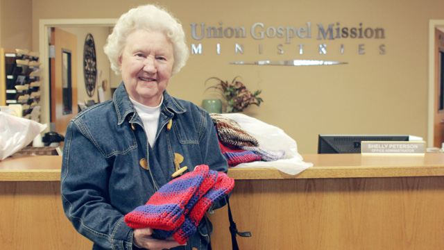 Lady donating knitted hats