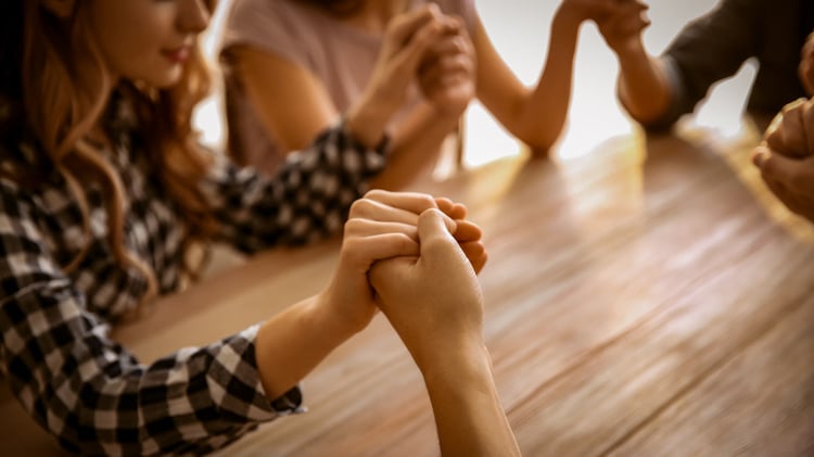 Women holding hands and praying