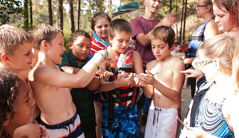 Campers gather around a small snake they found at UGM Camp. Getting away from the city and close to nature is an important part of the camp experience.