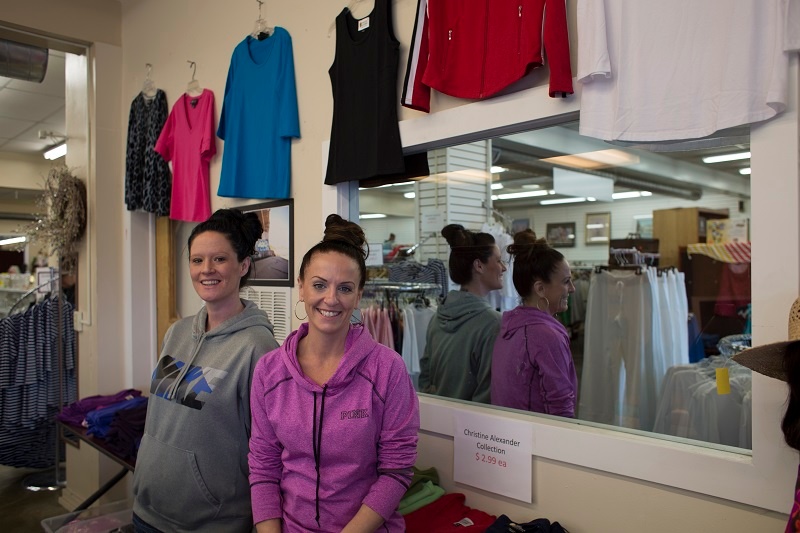 Lacey and Tiffany put out clothing for sale at the UGM Thrift Store